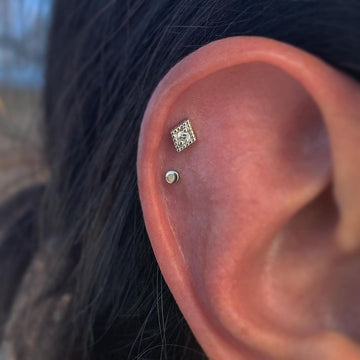 close up image of a double helix ear piercing with a diamond and a dot shaped earring from IRIS studio shop in Salt Lake City