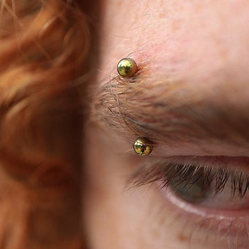 close up eyebrow piercing with gold jewelry done at the IRIS Salt Lake City shop