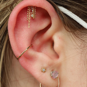 close up image of an ear with a helix piercing and two earlobe piercings done at  IRIS Portland Oregon studio