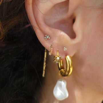 lobe with five ear piercings on it paired with diamonds and gold jewelry from IRIS Piercing Studio and shop in Salt Lake City Utah