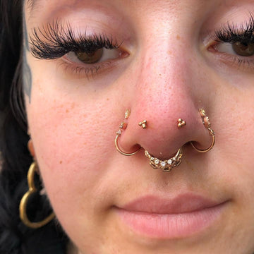 close up image of a woman's nose with several piercings on the sides and a septum face piercing in the middle