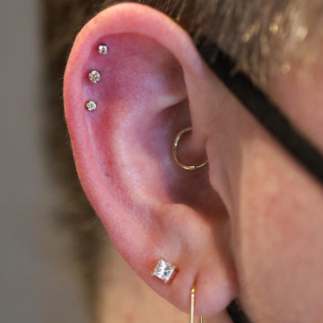 close up image of an ear with a triple helix piercing and two earlobe piercings done at  IRIS Portland Oregon studio
